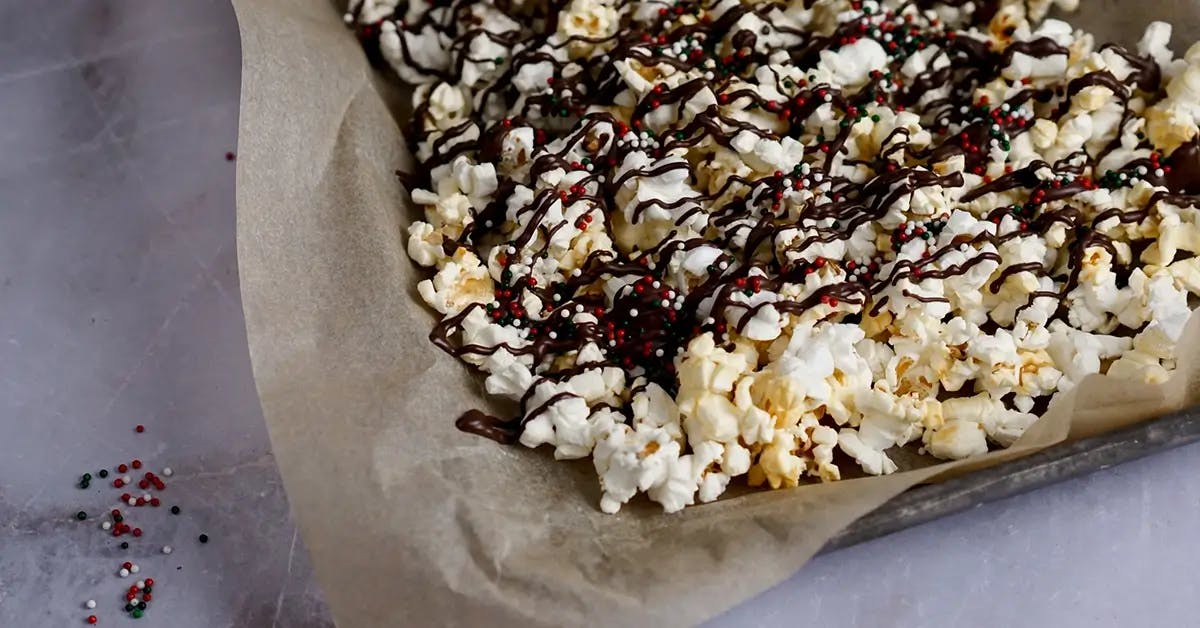 Christmas popcorn on a baking tray, drizzled with peppermint dark chocolate and sprinkles.