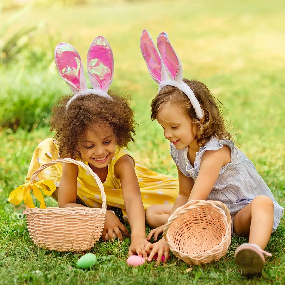 Two young girls with Easter baskets, finding eggs during an Easter egg hunt.