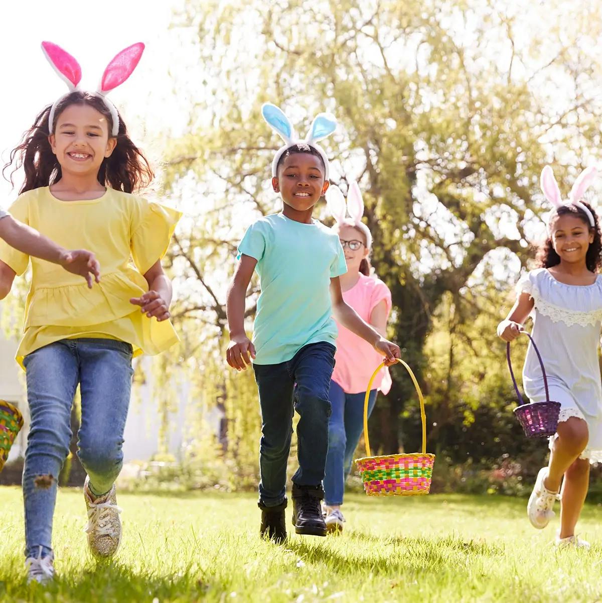 Children wearing bunny ears running to find easter eggs during an easter egg hunt.
