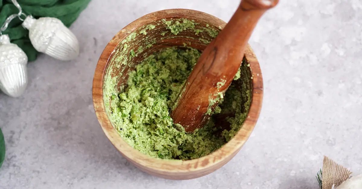 Pesto being prepared with a mortar and pestle for Christmas Pasta Salad.