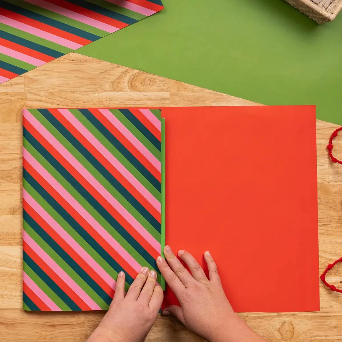 Folding wrapping paper to the edge of a book, in a tutorial on how to wrap a book.