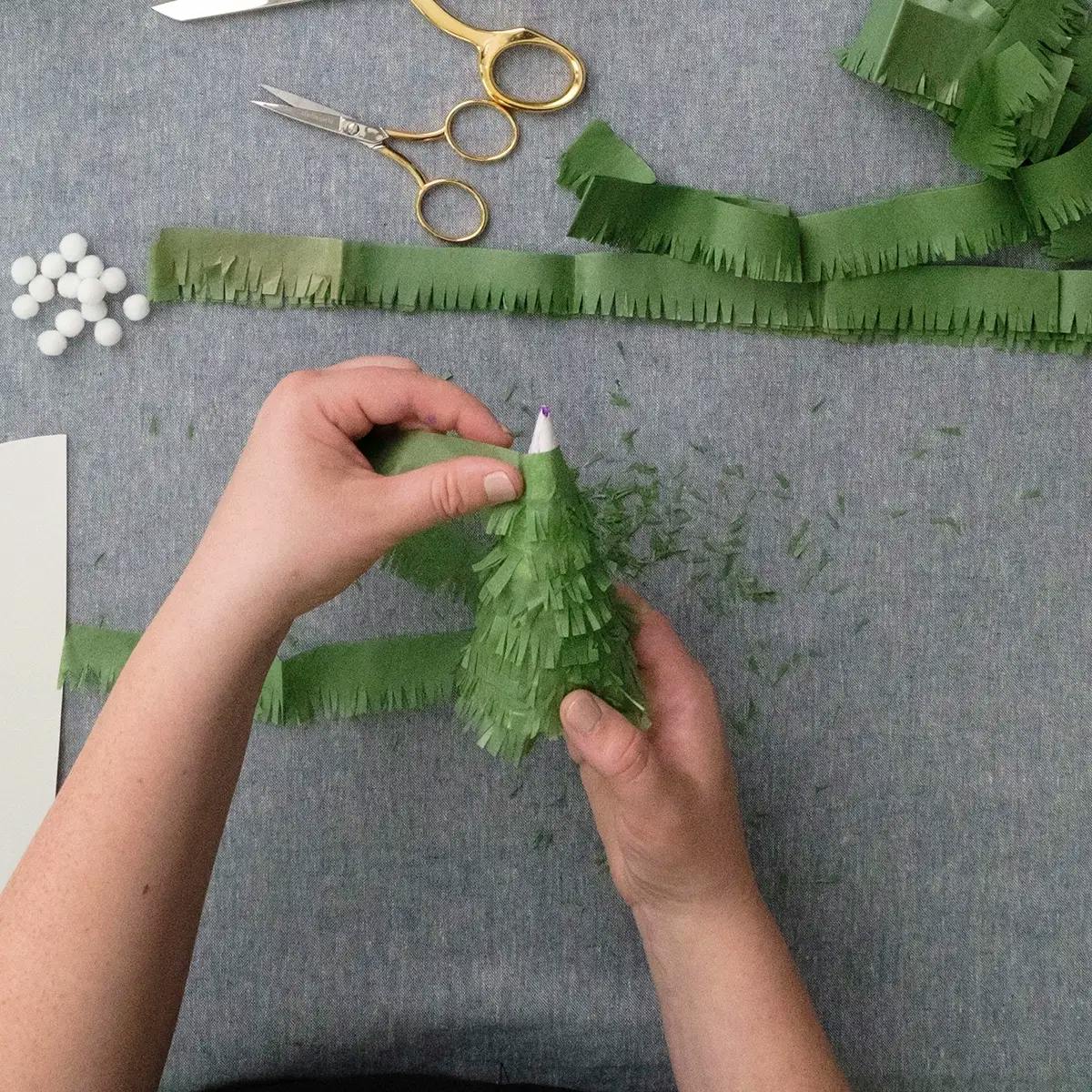 Glueing tissue paper to a cone as part of a paper tree decoration.