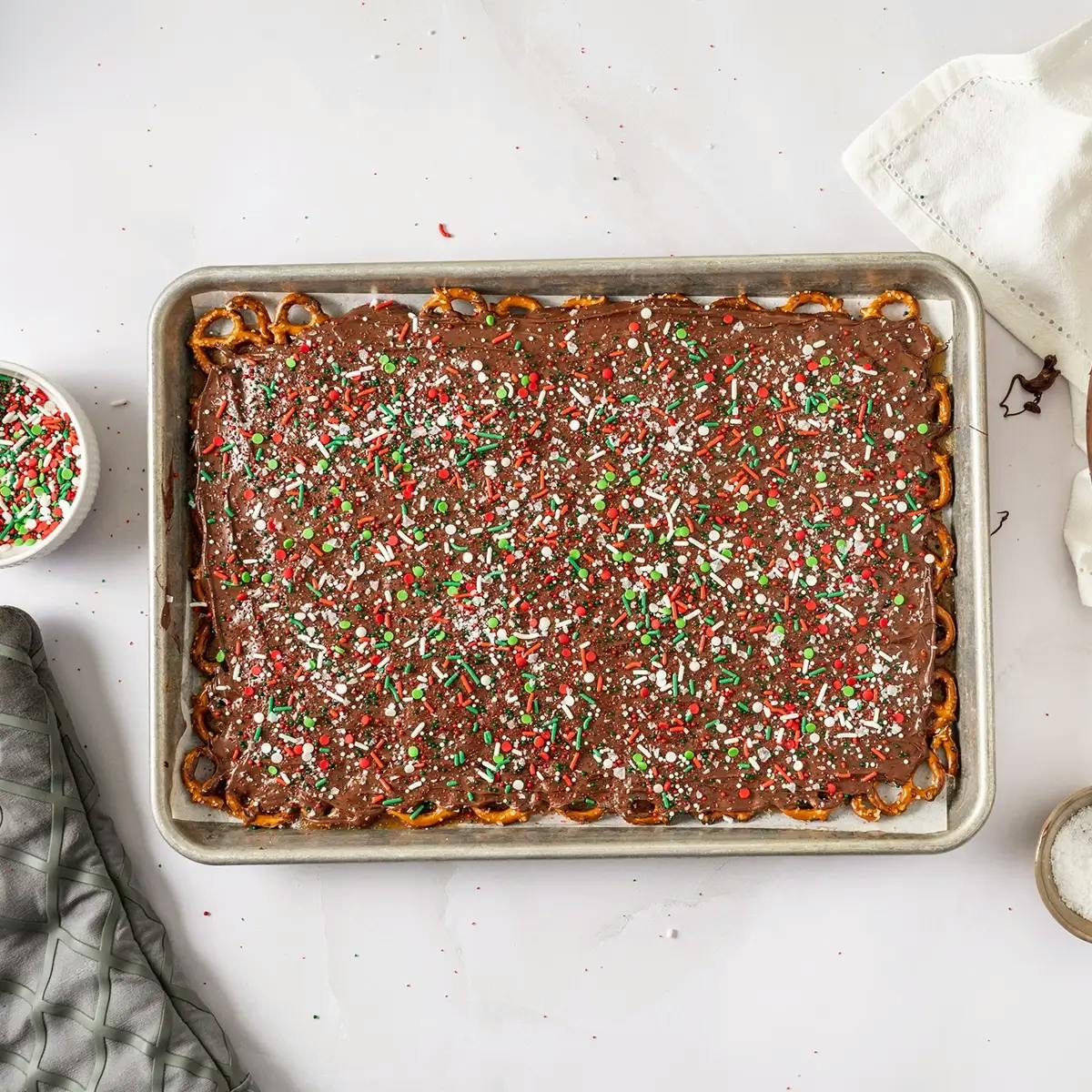 A tray of Christmas Crack with Pretzels, covered in sprinkles and left to cool.