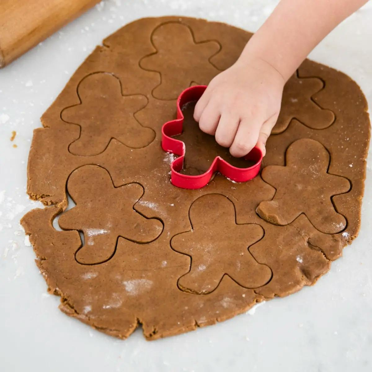 Cutting Gingerbread Men out of gingerbread cookie dough.