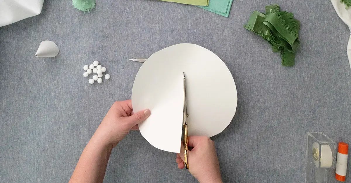 Cutting paper circles in half to create paper tree ornaments.