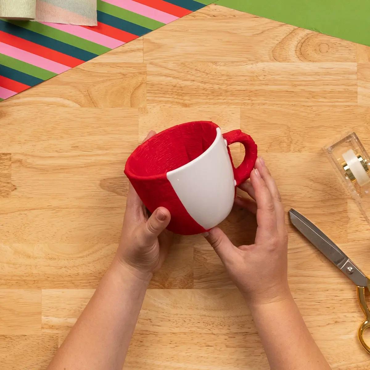 Adding crepe paper strips to cover a mug, in a tutorial on how to wrap a mug.