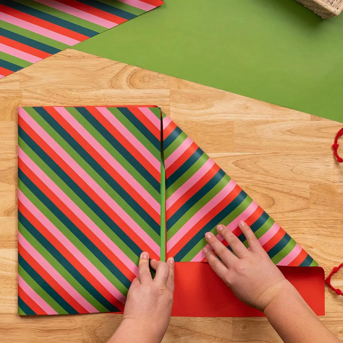 Making the second wrapping paper fold in a tutorial on how to wrap a book.
