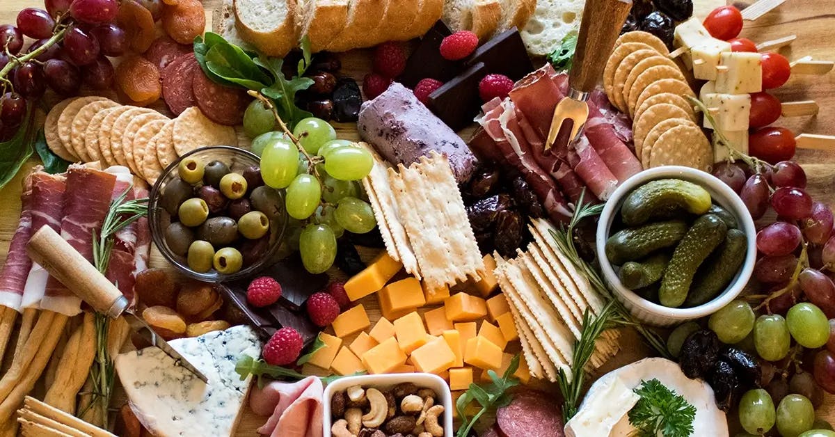 Christmas charcuterie board featuring meat, cheese, fruit, and crackers.