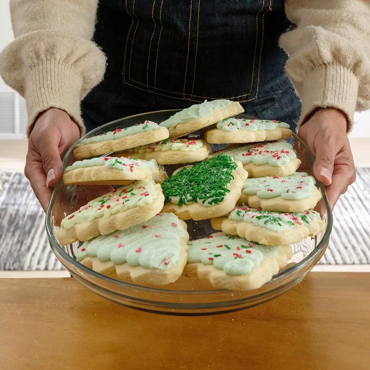 Hands holding a plate of cookies in an article containing Christmas cookie decorating tips.