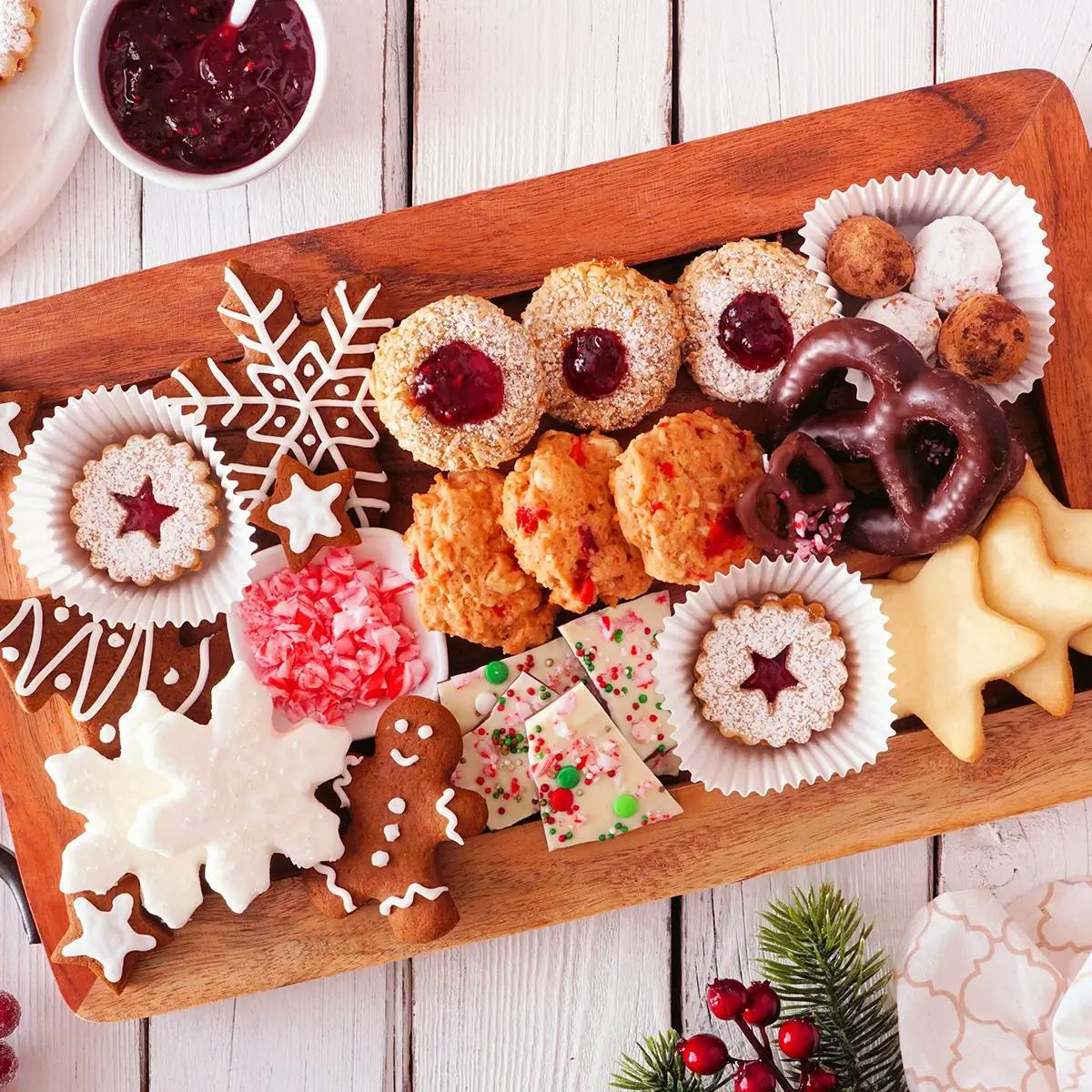 A Christmas dessert charcuterie board with cookies, gingerbread men, and cakes.