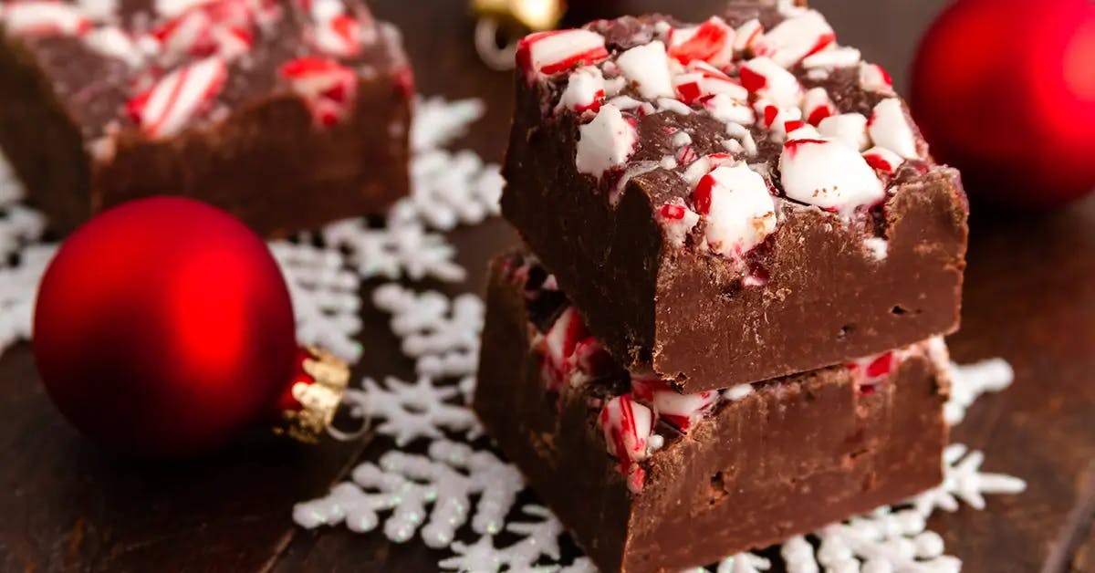 Chocolate microwave fudge topped with crushed peppermint candy canes, with a red holiday ornament to the left.