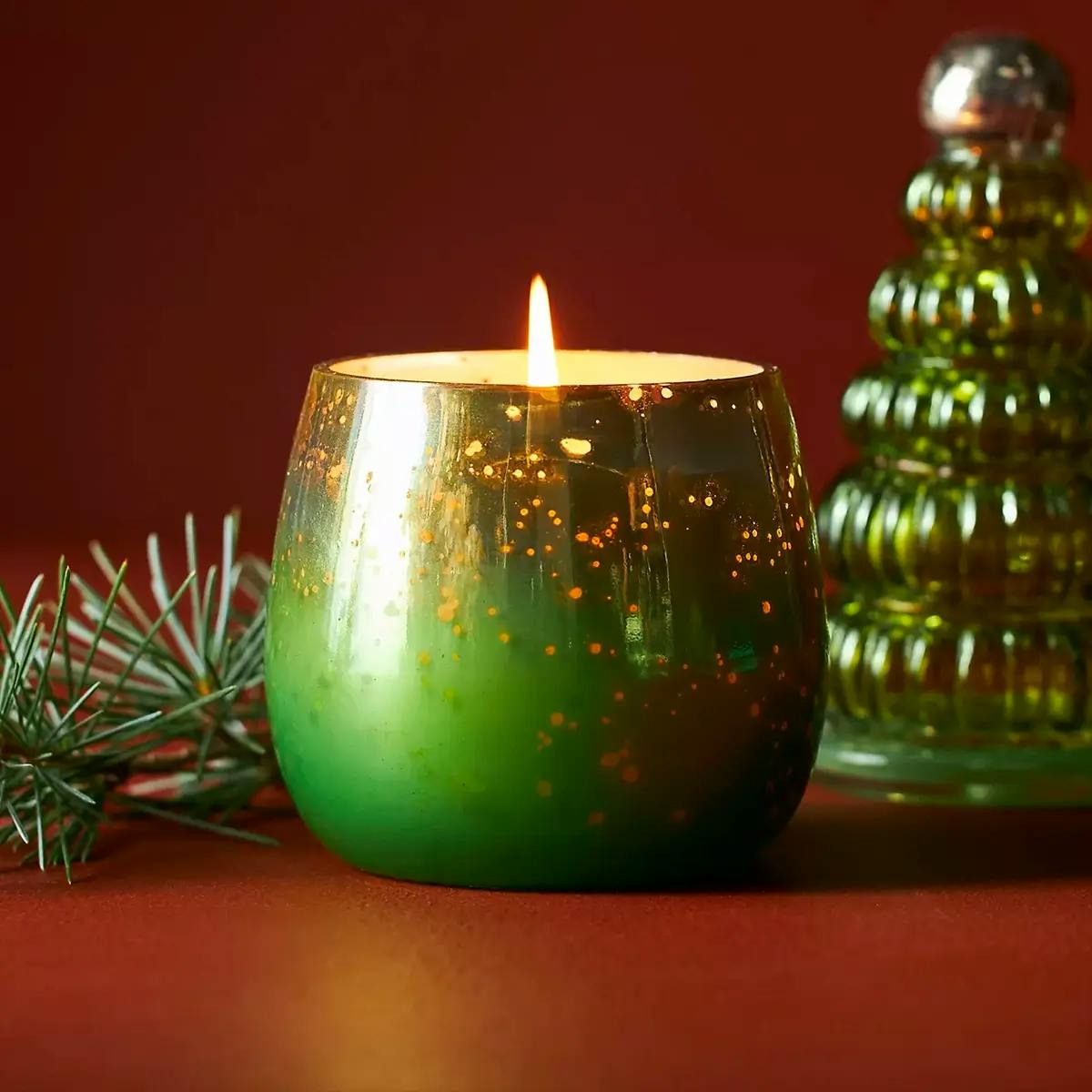  Green Treetop Christmas candle by Anthropologie, with glass fir tree-shaped top in background.