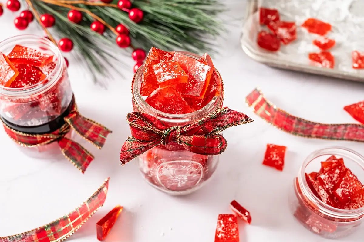 Cherry homemade Christmas candy in a jar tied with a red plaid ribbon.